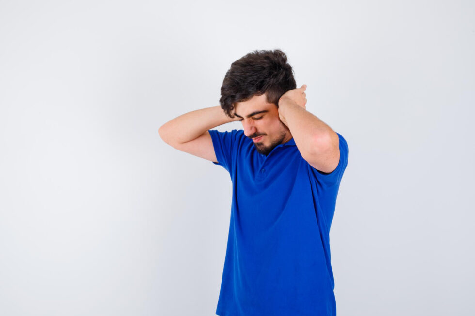 A person experiencing dizziness and discomfort holds both sides of their head, illustrating common symptoms of vertigo or balance disorders.