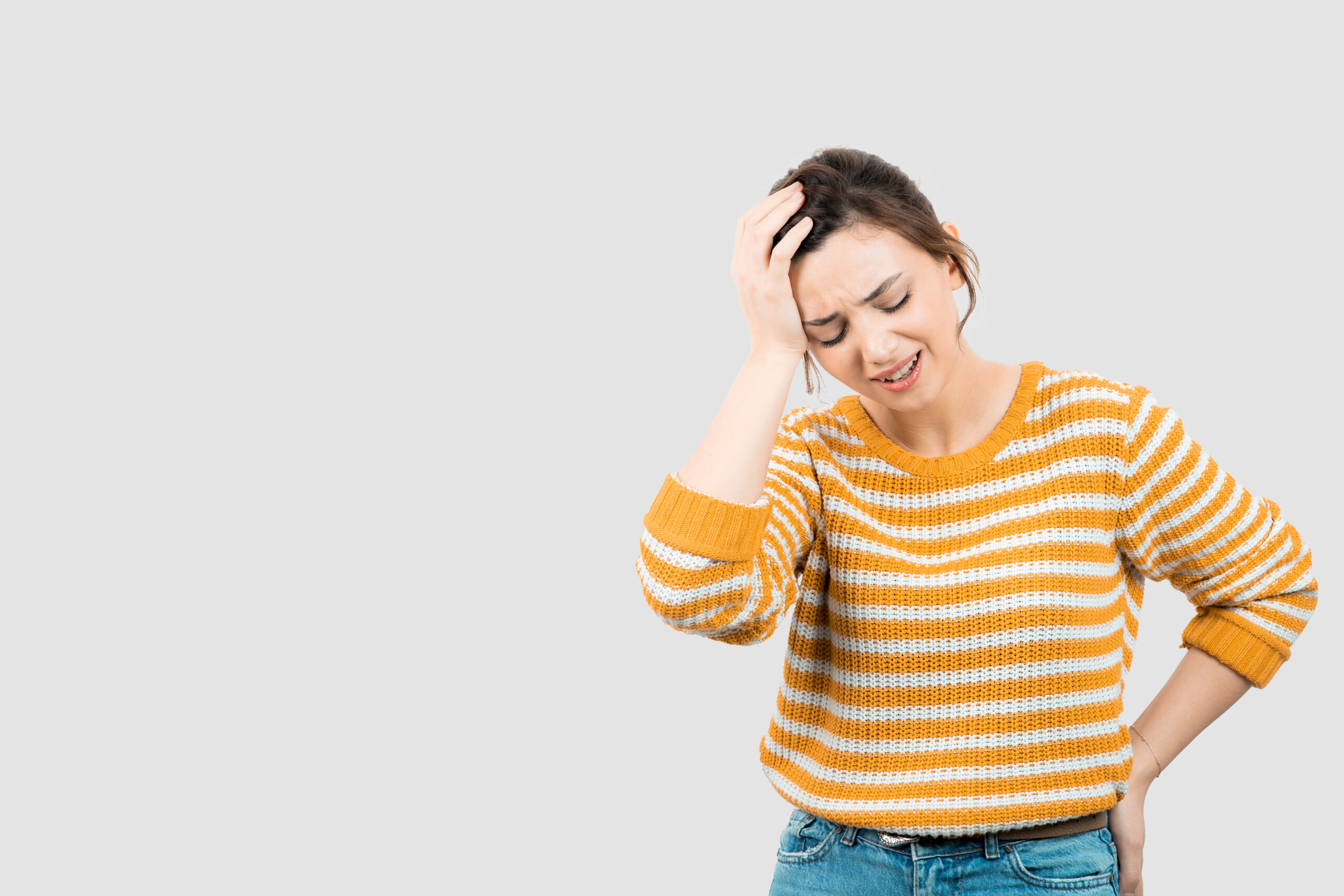 A young woman appears to be experiencing dizziness or discomfort, holding her head while standing.