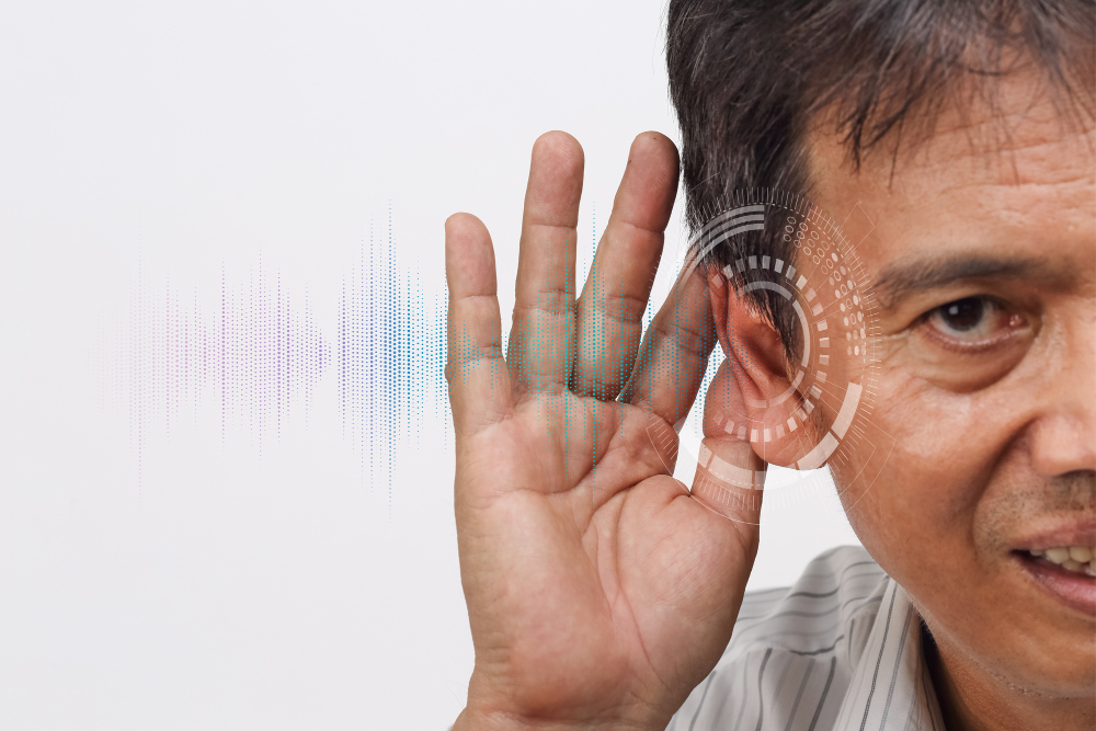 a middle-aged man cupping his hand behind his ear, symbolizing difficulty hearing.