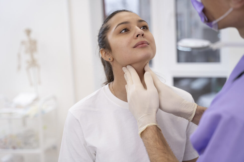a medical examination of the neck/throat area, where a healthcare professional is gently palpating the patient's neck