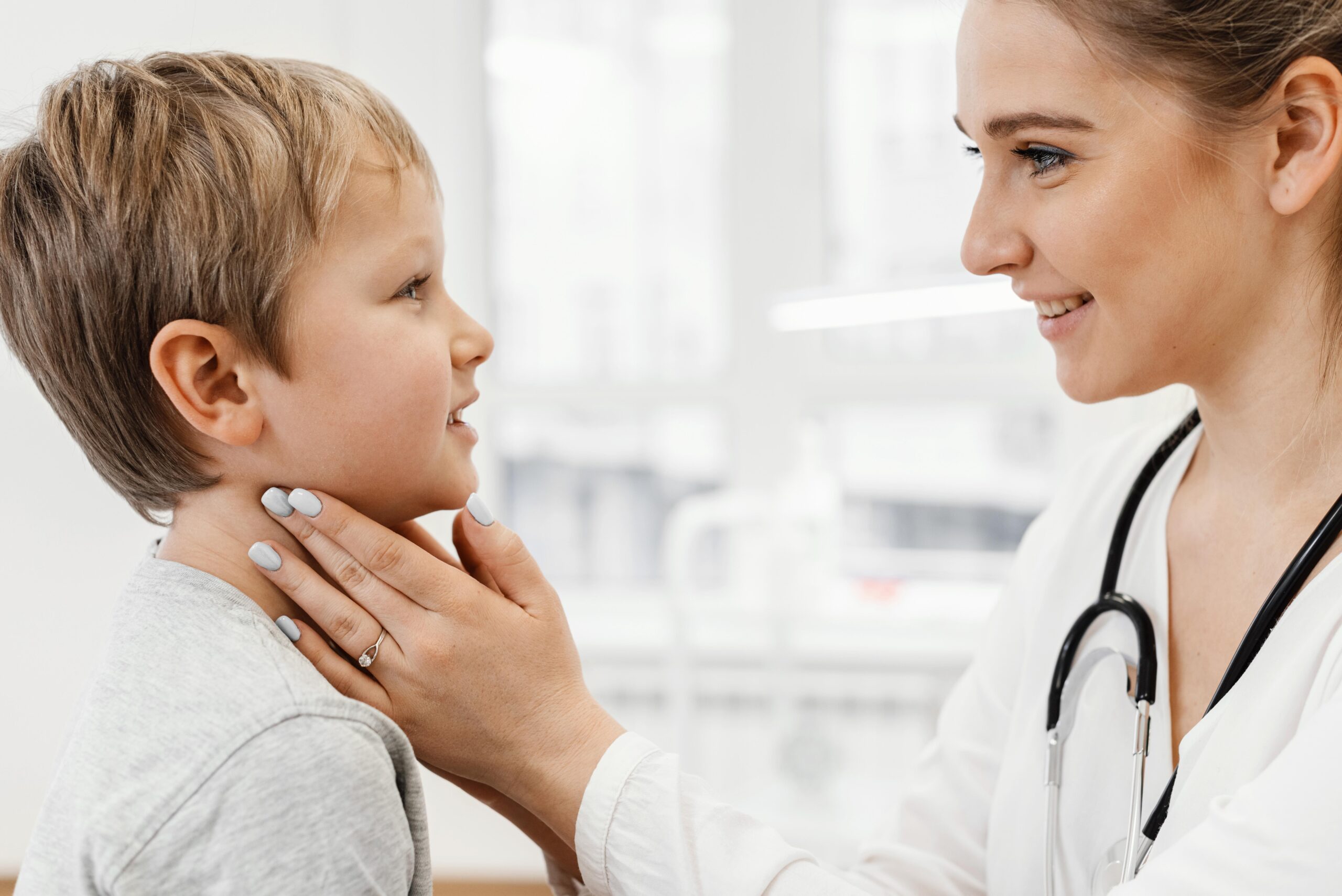 a child being examined by an ENT doctor, with the doctor checking the child’s neck and throat area.