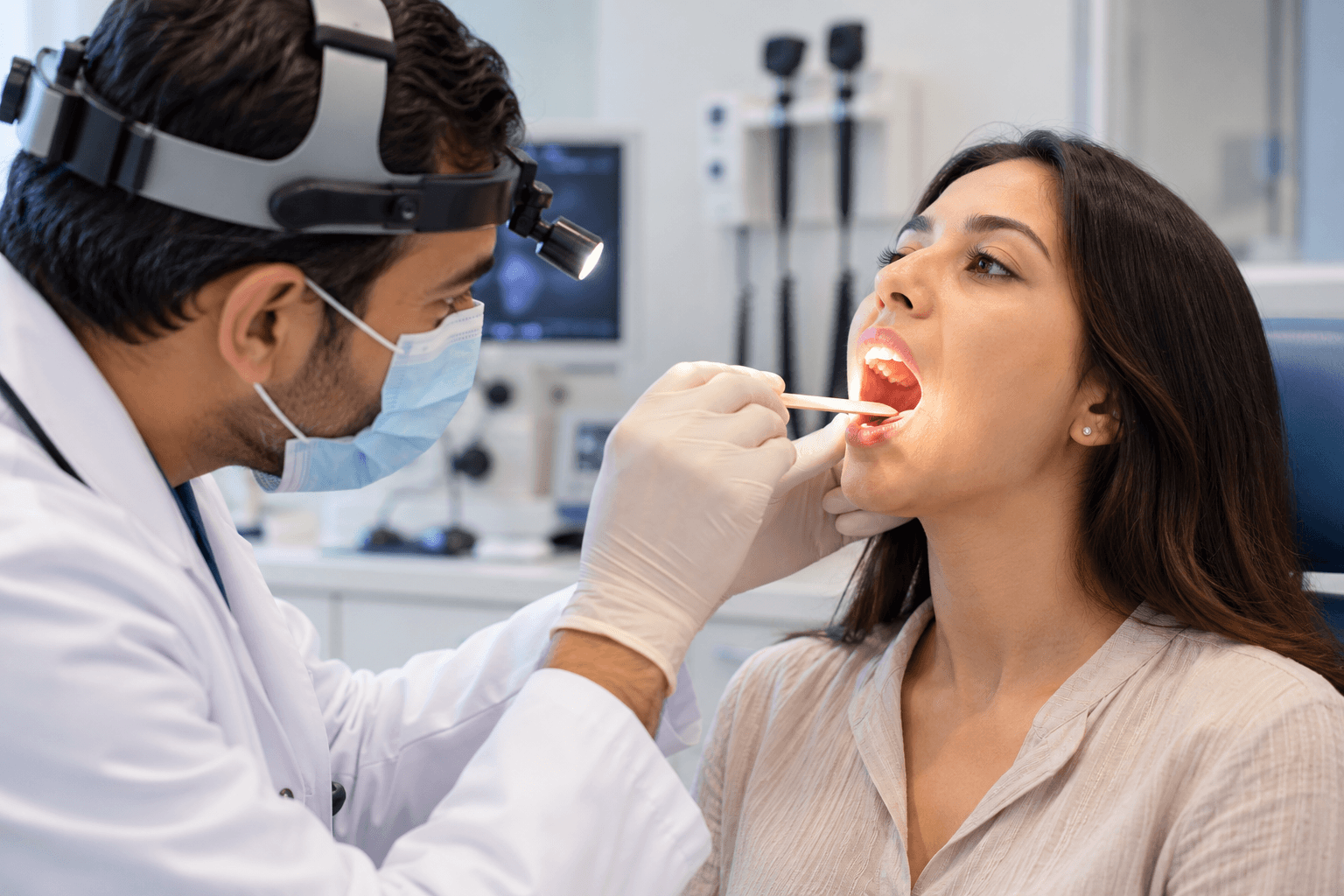 an ENT specialist examining a patient’s throat with a medical light or tongue depressor